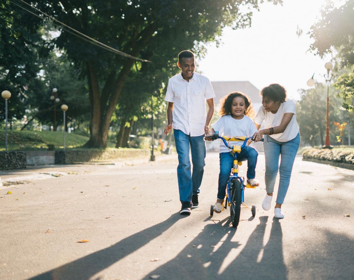 Young family walking together with their child in a sunlit park