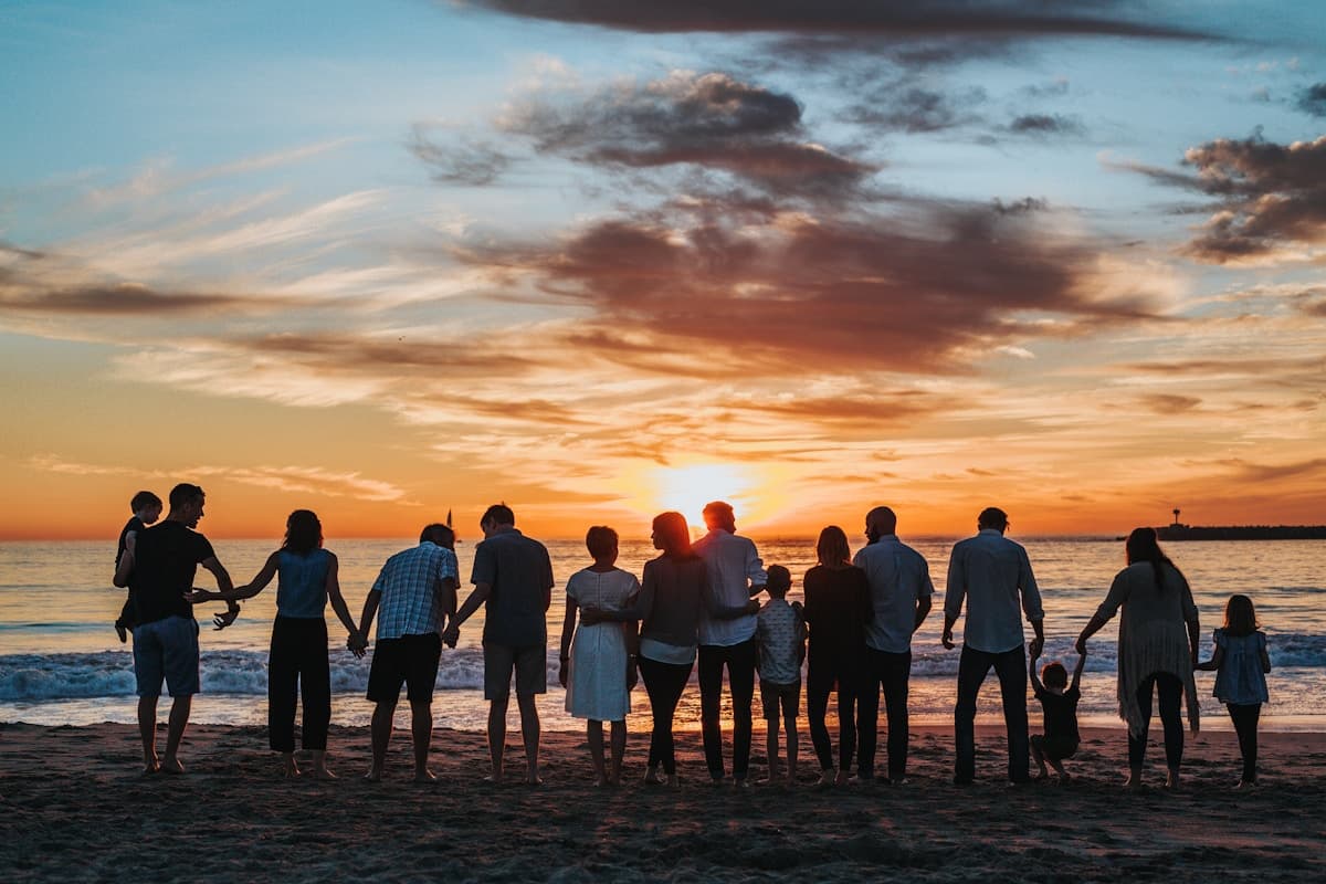 Multi-generational family silhouetted together on a beach at sunset